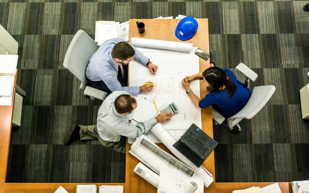 pexels photo 416405 416405 Top view of a team working on construction plans in an office setting.